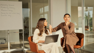 Two women executives reviewing marketing strategy in a sunlit conference room